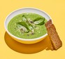A bowl of green soup made with courgette, leek and goat's cheese served with bread